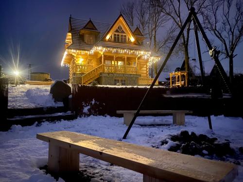 a house with christmas lights on it in the snow at Marusina Chalets in Szaflary