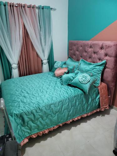 1 cama con sábanas y almohadas verdes en una habitación en SUISSE . CH APPARTEMENT, en San Pedro de Macorís