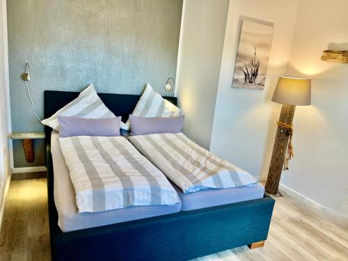Un dormitorio con una cama azul con almohadas y una lámpara en Hof Steinhütten, en Westerhever