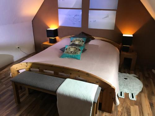 a bedroom with a bed with a bench and two lamps at Haus Horizont in Dyksterhusen