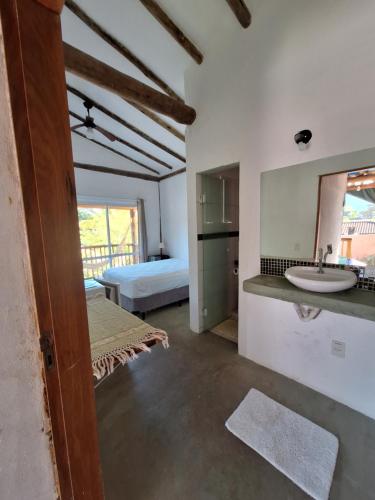 La salle de bains est pourvue d'un lavabo et d'un lit dans la chambre. dans l'établissement Alma Surf House, à Boicucanga