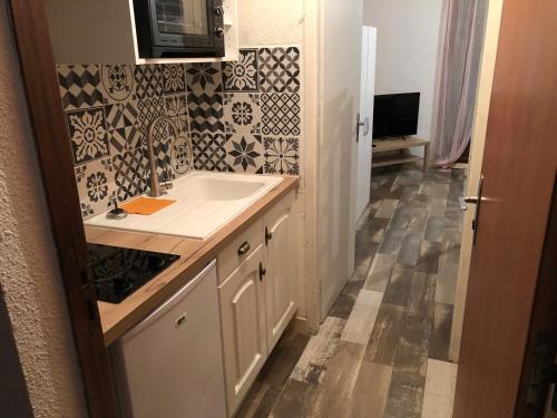 a bathroom with a sink and a tile wall at STUDIO LES JONQUILLES in Les Angles