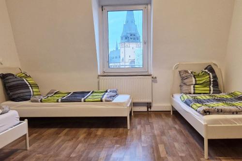 two beds in a room with a large window at Apartments Leverkusen in Leverkusen