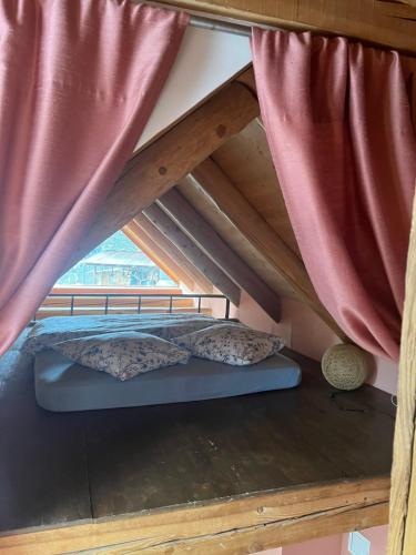 a bed in a attic with red curtains at Casa Viola in Piano