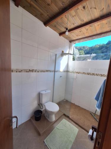a bathroom with a white toilet and a window at Alma Surf House in Boicucanga