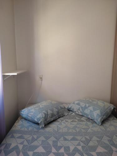 a bed with two pillows in a room at Um quarto em casa agradável in Perequê