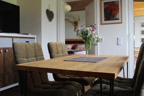 a dining room table with a vase of flowers on it at Ferienhaus Schau ins Land - eigene Panorama-Sauna in Schöfweg