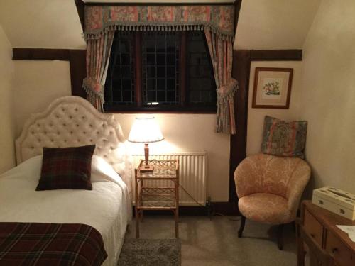ein Schlafzimmer mit einem Bett, einem Stuhl und einem Fenster in der Unterkunft Apartment in an historic farmhouse in Burgess Hill
