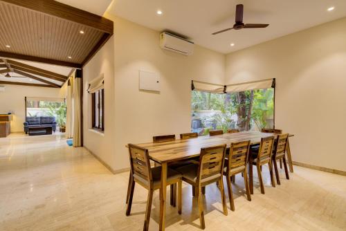 Saligao的住宿－Tropical villa by Happyinch，一间带木桌和椅子的用餐室