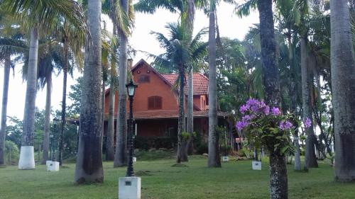 een huis omgeven door palmbomen en paarse bloemen bij Terra Rica Summer House in São Pedro