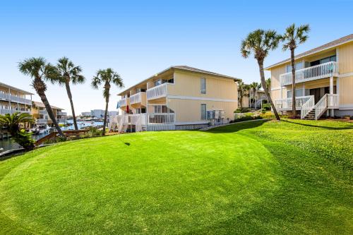 a golf course with palm trees in front of condos at ​Sandpiper cove in Destin