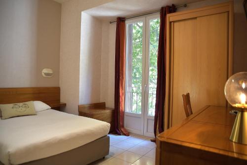 sypialnia z łóżkiem, biurkiem i oknem w obiekcie Hotel Bonaparte w Bastii