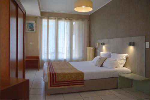 a bedroom with a bed with white sheets and pillows at Hotel Bonaparte in Bastia