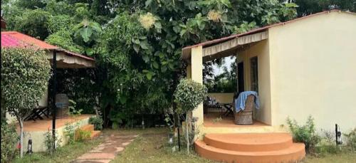 una pequeña casa blanca con un banco en un patio en Ranthambore Jungle Home, en Khilchīpur