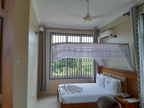 a bedroom with a bed and a large window at WILIVINA HOTEL in Dar es Salaam