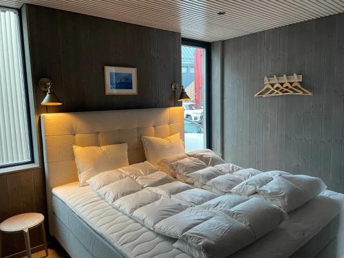 Cette chambre comprend un grand lit avec des oreillers blancs. dans l'établissement Waterfront apartment with panoramic sea view, à Henningsvær