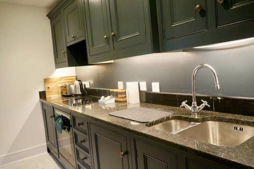 een keuken met groene kasten en een wastafel bij Epic Location, Views & Large Private Terrace in Windsor