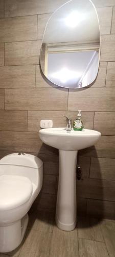 La salle de bains est pourvue d'un lavabo blanc et d'un miroir. dans l'établissement Habitación totalmente independiente con cocina, baño, balcón super espacioso, à Arequipa