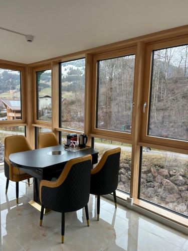 a dining room with a table and chairs and windows at Crystal Vista in Zweisimmen