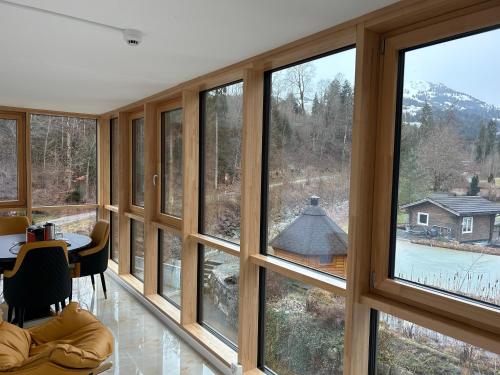 Cette chambre dispose de grandes fenêtres avec une table et des chaises. dans l'établissement Crystal Vista, à Zweisimmen