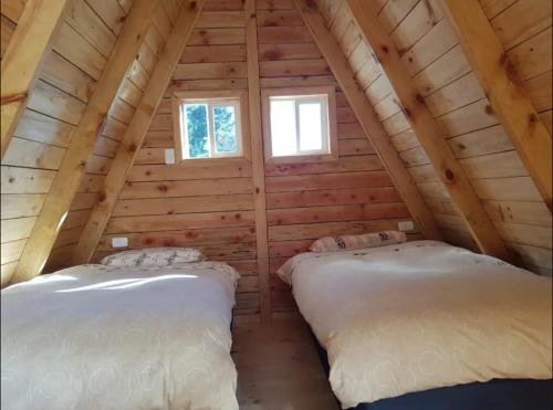 duas camas no sótão de um chalé de madeira em Linda cabaña en Puyehue con vista al volcán em Ñilque