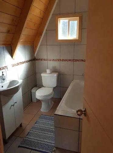 a bathroom with a toilet and a tub and a sink at Linda cabaña en Puyehue con vista al volcán in Ñilque