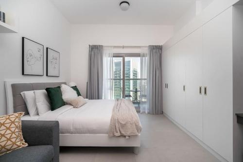 - une chambre blanche avec un lit et un canapé dans l'établissement HiGuests - Bella Rose Studio With Stunning Desert Views, à Dubaï