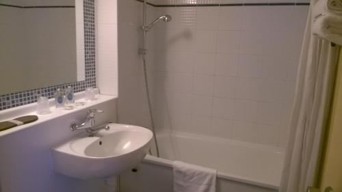 a white bathroom with a sink and a shower at Kyriad Mulhouse Est - Lutterbach in Lutterbach