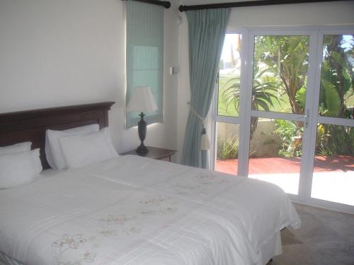 Un dormitorio con una cama blanca y una ventana grande. en Waterside Living MM1404, en Jeffreys Bay