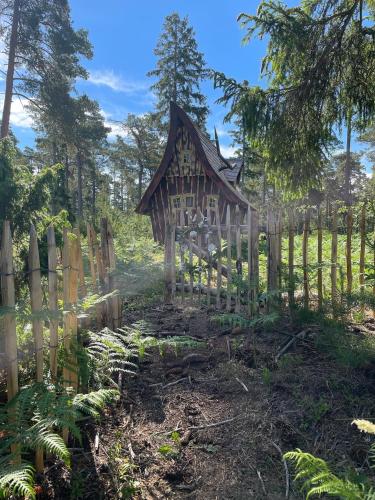 una pequeña casa de madera en un jardín con una valla en Fairytale tinyhouse near the sea - Häxans hus en Gothem