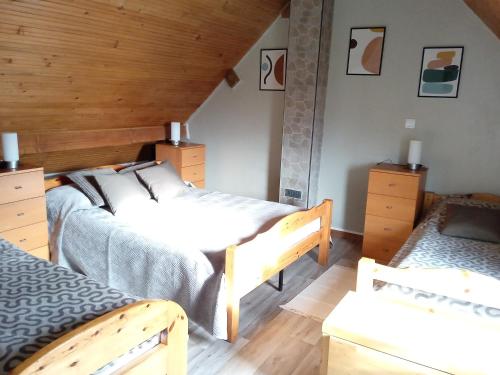 two beds in a room with wooden walls and wooden floors at Maison de vacances Sol & Piper in Gombergean