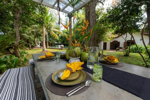 a wooden table with plates and napkins on it at MO River House Luxury Villa in Hikkaduwa