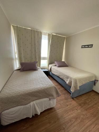 2 camas en una habitación pequeña con ventana en Departamento condominio Laguna del Mar, en La Serena