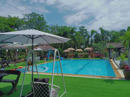 a pool with an umbrella and chairs and a table at บาคัสโฮมลอร์ด in Haad Chao Samran