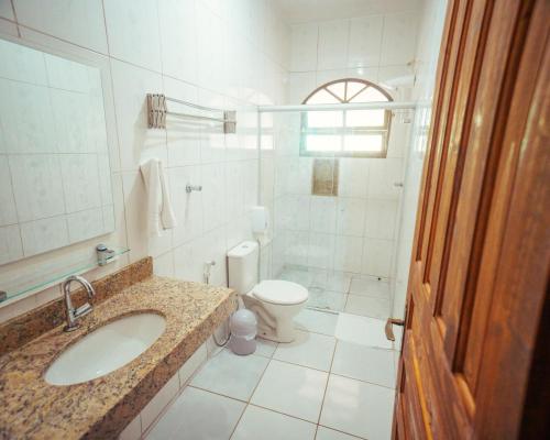 a white bathroom with a sink and a toilet at Pousada Flores do Lázaro in Ubatuba