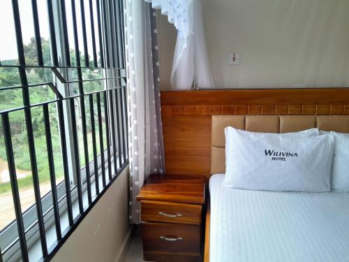 a bedroom with a bed and a large window at WILIVINA HOTEL in Dar es Salaam