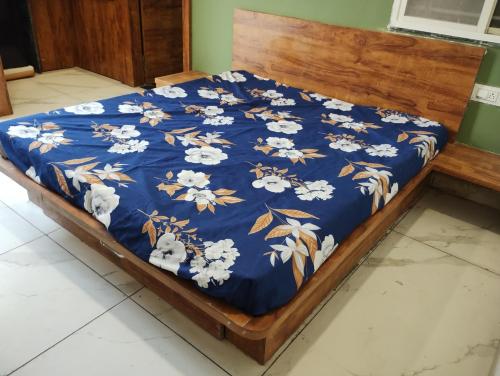 uma cama com um cobertor azul com flores brancas em Smart living Opal em Indore