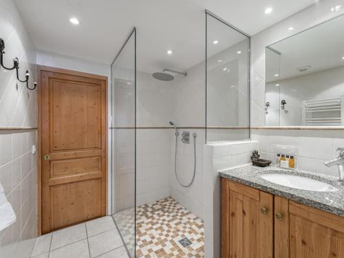 La salle de bains est pourvue d'une douche, d'un lavabo et d'une porte en verre. dans l'établissement Appartement Confortable 6 Pers. Proche des Pistes avec Balcon et Parking - FR-1-640-11, à Val Thorens