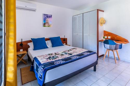 a bedroom with a bed with blue pillows at Le KAWAN NID, Marie-Galante appartement avec climatisation, wifi , à proximité d'une plage et d'une piscine privée in Grand-Bourg