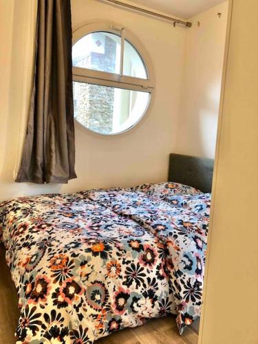 - une chambre avec un lit avec une couette à fleurs et une fenêtre dans l'établissement Flat in Choisy Le Roy, 6 min from Paris, à Choisy-le-Roi