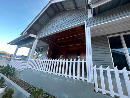 two people sitting on the porch of a house at T.P Homestay in Mechuka