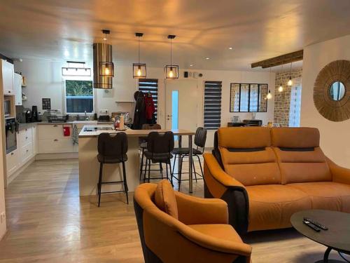 ein Wohnzimmer und eine Küche mit einem Sofa und Stühlen in der Unterkunft La Montbourgeoise in Montebourg