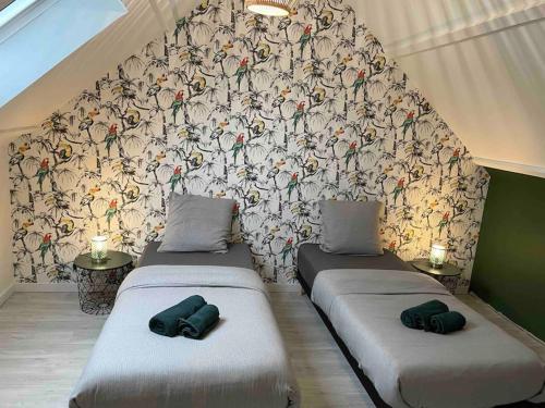 2 Einzelbetten in einem Zimmer mit Tapete in der Unterkunft La Montbourgeoise in Montebourg