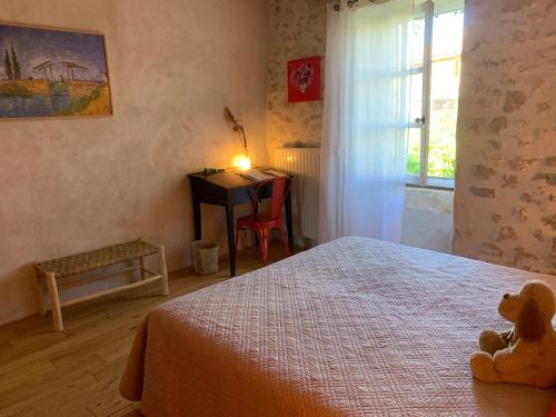 een slaapkamer met een bed en een bureau met een teddybeer bij La Magnanerie de Dions in Dions