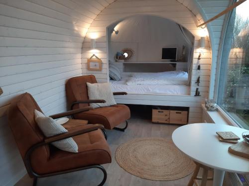 a room with a bed and two chairs and a table at Tiny House De Boet, in Natuurgebied en vlakbij het Strand in Callantsoog