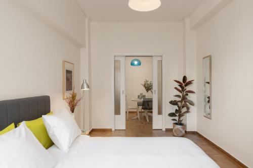 a bedroom with a white bed and a dining room at Lovely Apartment in Exarcheia in Athens