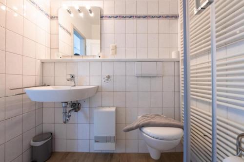 Baño blanco con lavabo y aseo en Haus Nordstrand FeWo Zingst, en Prerow