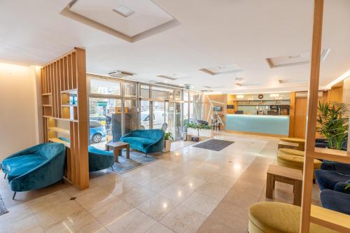 a waiting room with blue chairs and tables at Medos Hotel in Budapest