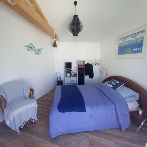 - une chambre avec un lit bleu et une chaise dans l'établissement La désirée à Noirmoutier, à Noirmoutier-en-l'lle