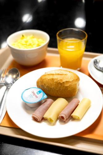 a plate of hot dogs and bread and a glass of orange juice at HUS Hotel MARINGA in Maringá